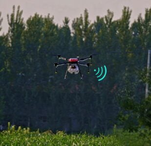 A small drone hovering above a vast field, capturing aerial views.