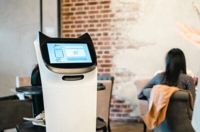 Robot waiter serve food at modern restaurant table.Offering innovation futuristic high-tech automated dining experience.Bringing,delivery automation order to customer.Digital robotic AI smart service.